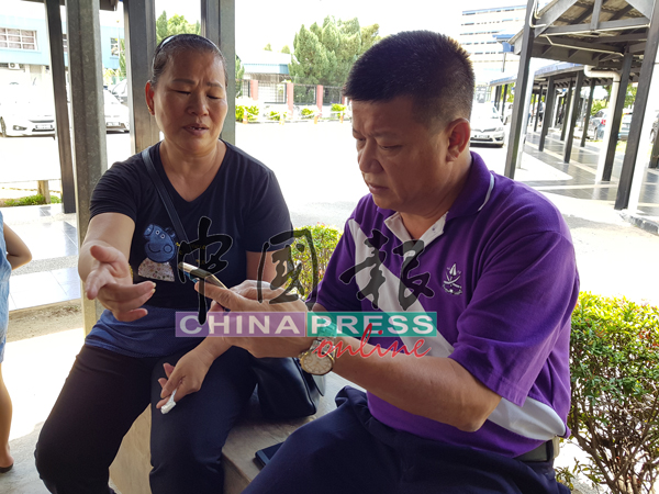 鄒美蓮（左）向沈春祥展示女兒彩玲住院後的視頻。