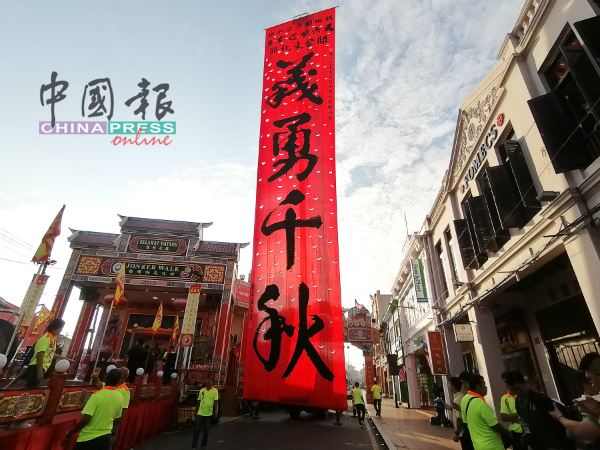 由赵友福挥毫的巨型条幅“义勇千秋”，竖立在甲市鸡场街文化坊舞台旁，形成壮观场面。