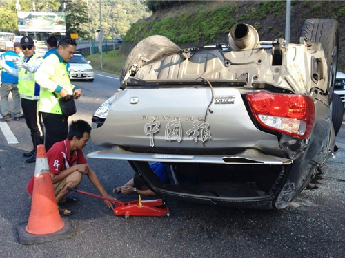 華裔男子使用千斤頂將轎車移高，將壓在車下的巫裔傷者救出。