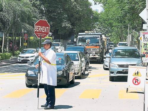 学校外的两旁道路泊满车子，双向道宛如剩下一条车道，让驾驶人士寸步难移。