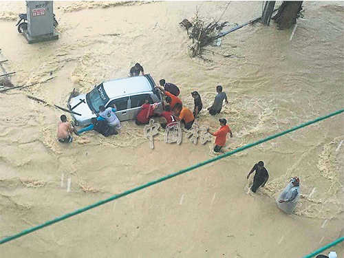 一輛轎車受困在水流中，多名村民合力將其推走。