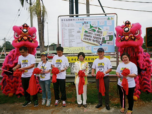 嘉賓在新立的峇冬加裡新村人文地圖前進行剪綵儀式，左起烏雪新村事務協調官黃德銘、陳惠詩老師、烏雪縣議員劉世興、州議員李繼香、烏雪旅游協會主席白榮盛、村長白文秀。