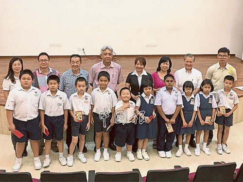  ■巫鳴鳳（后排右4）在涂美玲（后排左起）、劉國榮、賴善習、謝立意、蕭遠桃、賴善業和楊偉光陪同下，贈送10份125令吉的現金禮券，給新華小學學生。