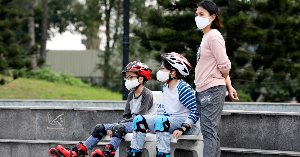 越南大人和小孩24日戴上口罩在河内公园休闲游玩。