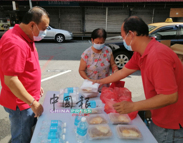 赖庆中（左）及梁证法（右）派发饭盒给长者。