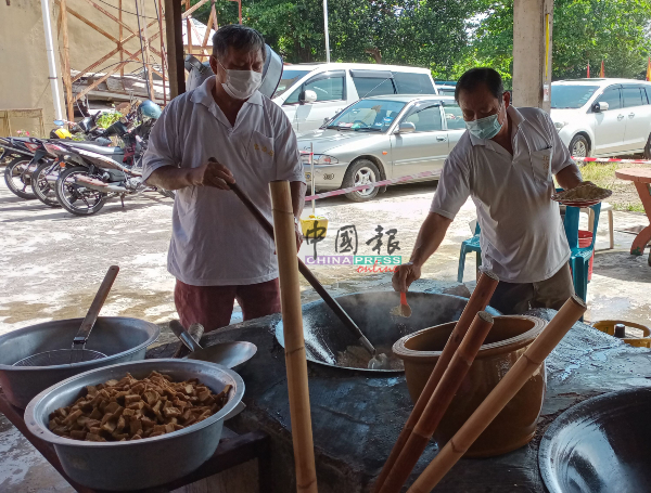 北添宫膳食组负责人张健荣（右）与志工一同烹煮斋菜，准备派发给善信。