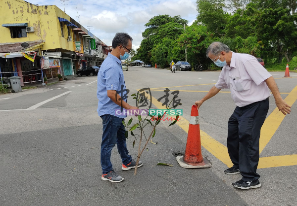 刘誌俍（左起）及陈劲源用路锥提醒公路使用者，小心路洞。