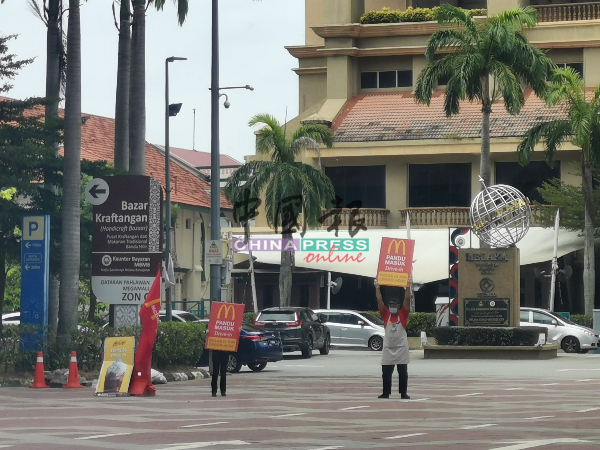 英雄广场麦当劳快餐店生意受影响，员工被迫在街边打广告，吸引食客“得来速”点餐。