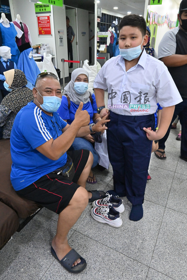 依斯萨德鲁斯（坐者）为在MCO 2.0期间长胖的儿子莫哈末法立斯新添校服。