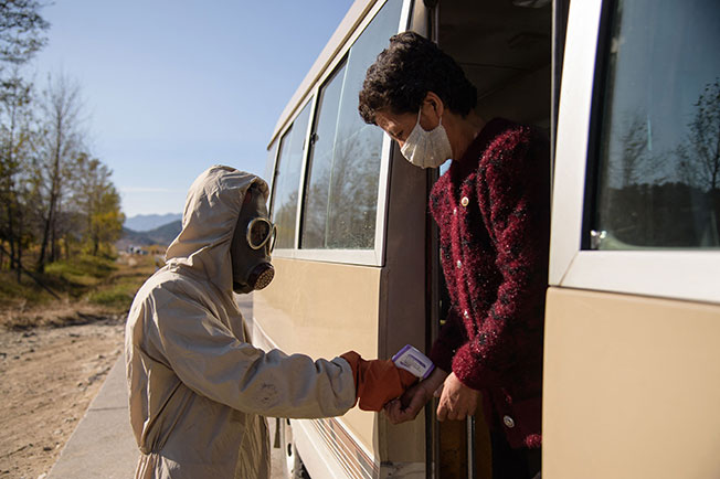朝鲜江原道元山市的卫生防疫工作人员，2020年10月29日对巴士乘客测量体温。（法新社档案照）