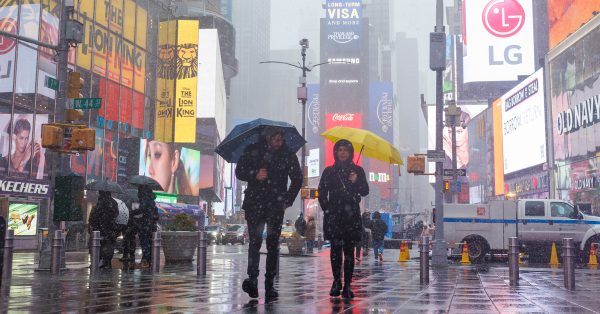 周二在纽约时报广场，民众在雪中步行。（欧新社）