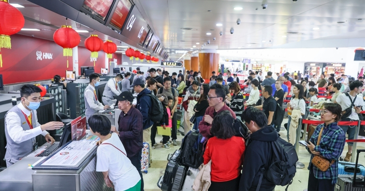 海南海口美兰国际机场迎来客流高峰，旅客周四在美兰国际机场T1航站楼，排队办理值机手续。（中新网）