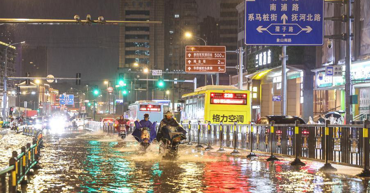 中国江西省南昌市一条道路周二晚上积水明显，市民骑摩哆涉水而过。 （中新社）