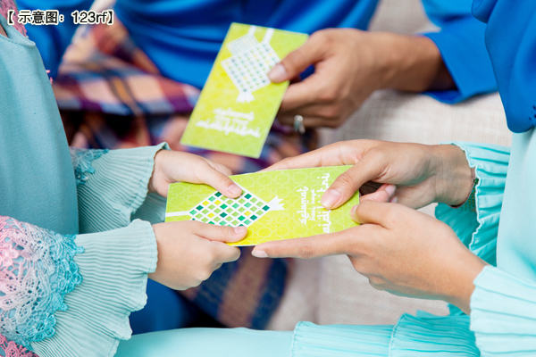 Close up of a Muslim girl receiving green envelopes from parents during Eid al-Fitr