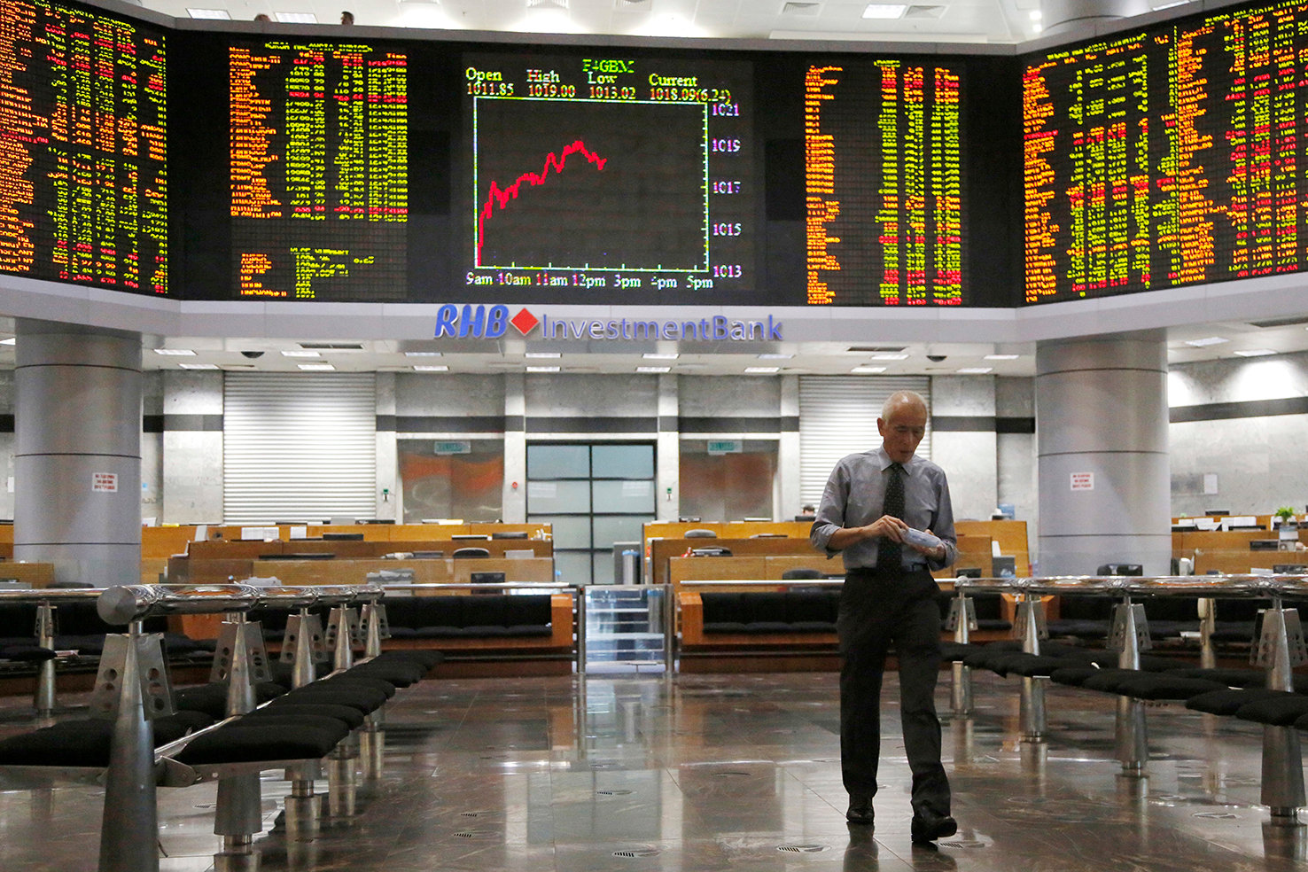 Investor walks in front of private stock trading boards at a private stock market gallery in Kuala Lumpur, Malaysia, Thursday, Aug. 23, 2018. (AP Photo/Yam G-Jun)